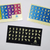 Imagen de adhesivos para teclado, con fondos negro, azul degradado y multicolor tonalidad arcoíris, con manos haciendo lengua de señas en tonalidad anarilla