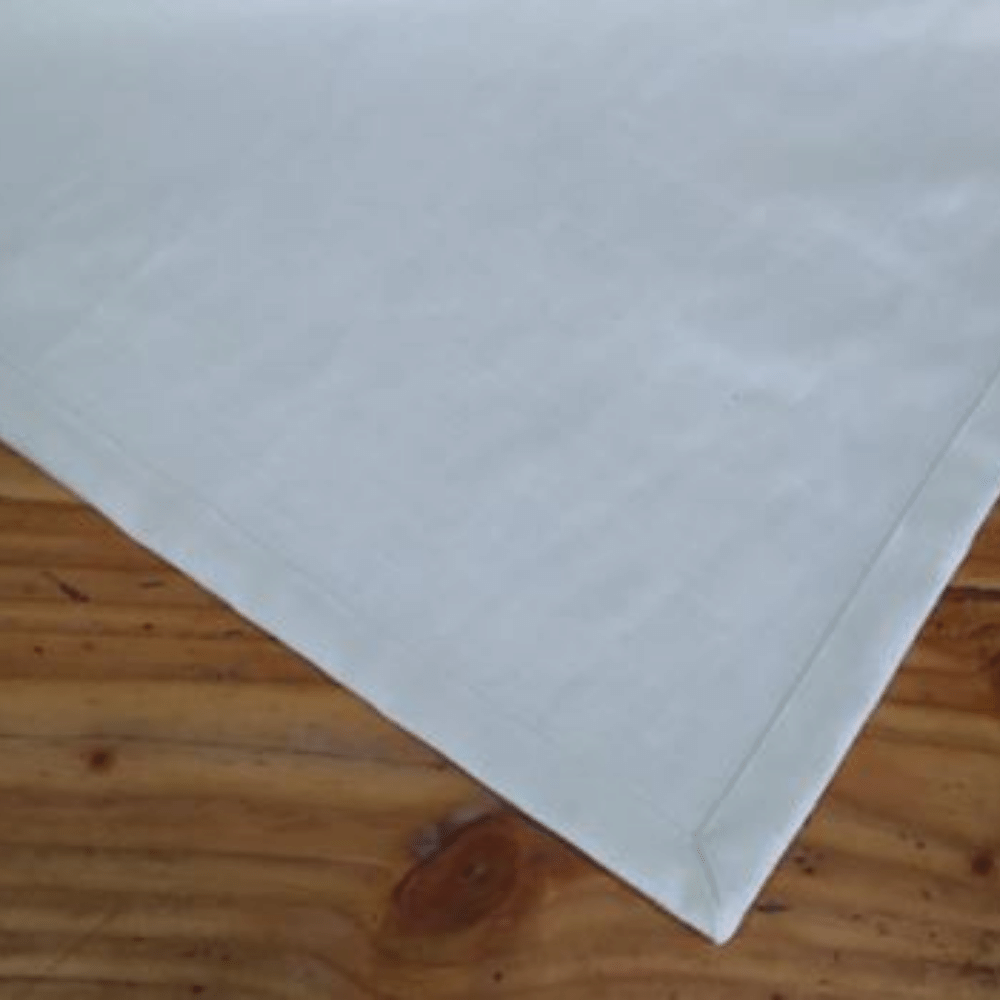 Se muestra la esquina del mantel de lino color crudo, se muestra la parte de la costura