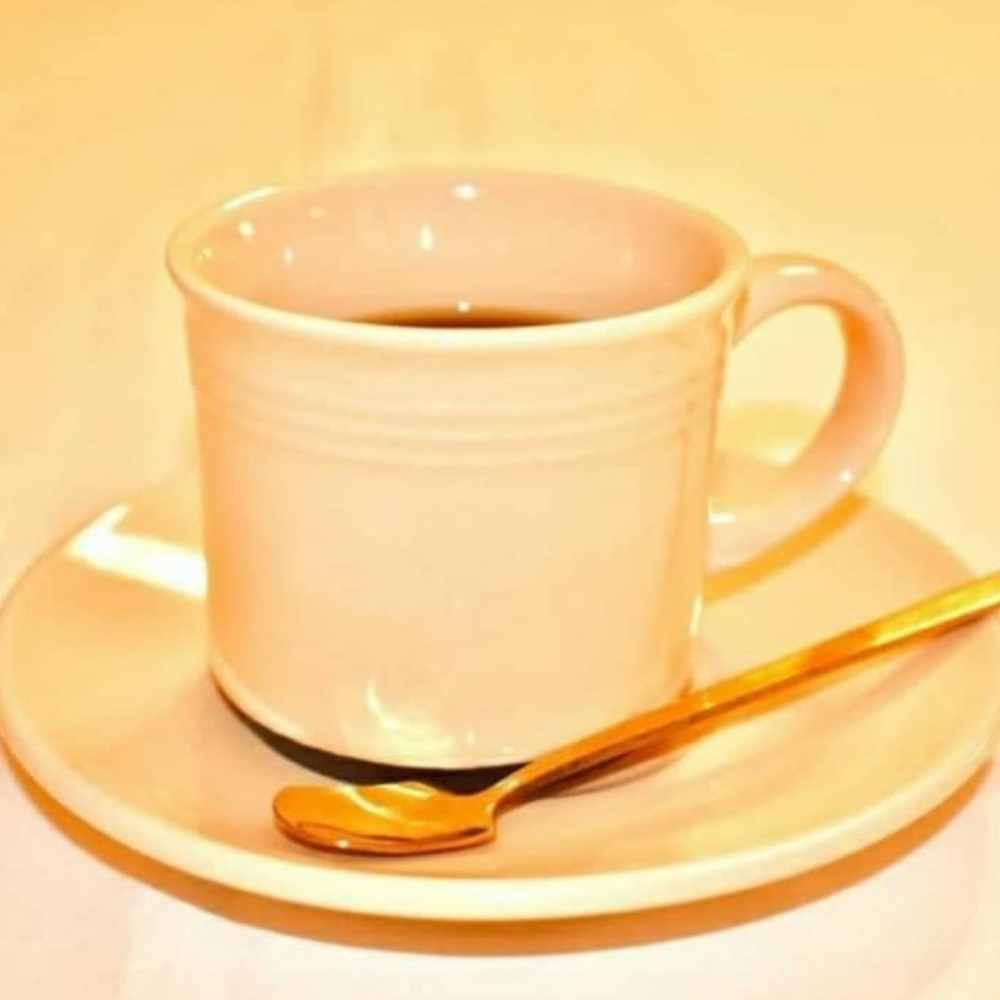 Foto de una taza con platillo y una cucharita dorada